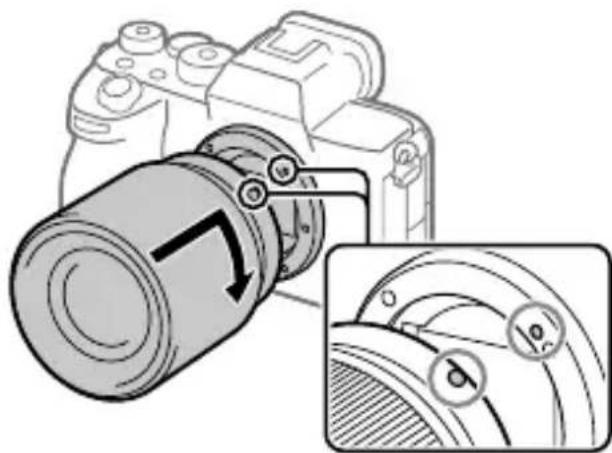 SONY Alpha A7S III - Mens du justerer de hvide indeksmærker (monteringsindekser), skal du forsigtigt skubbe objektivet mod kameraet. Drej derefter objektivet langsomt i pilens retning, indtil det klikker på plads. - 1