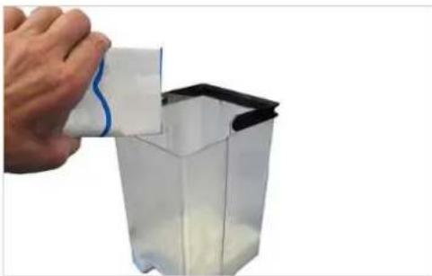 Hand pouring liquid into a transparent container with white powder (no text or symbols visible)