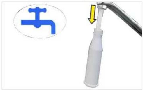 Close-up of a white plastic tool with a blue faucet icon and a yellow arrow pointing to it, next to a metallic pipe (no text or symbols).