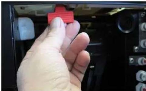 Hand holding a red 3D printer icon in a control panel (no visible text or symbols).