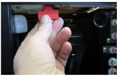 Hand holding a red 3D button on a device panel (no visible text or symbols)