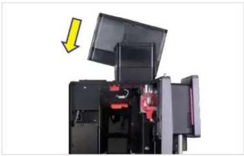 Interior view of a black industrial machine with open lid and red internal components, showing a yellow arrow pointing to the component (no text or symbols visible)