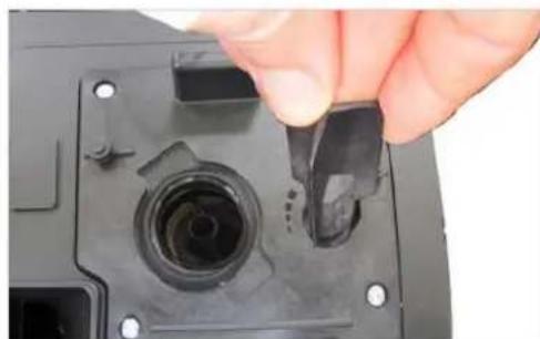Close-up of a hand holding a small black plastic component with a circular opening, mounted on a black electronic device (no visible text or symbols)
