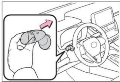 Diagram showing a hand pressing a car's steering wheel, with an inset highlighting the motion of the turn.