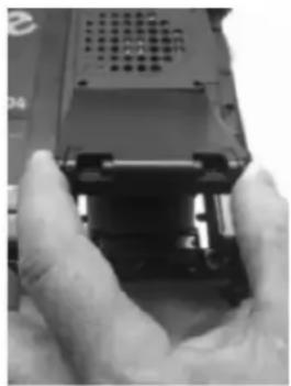 Close-up of hands holding a black mechanical component, possibly a device or device with no visible text or symbols.
