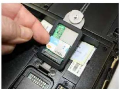 Close-up of a hand inserting a small electronic device into a laptop case (no visible text or symbols)