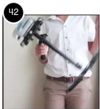 Person holding a black handheld device with a white shirt, standing indoors (no visible text or symbols)