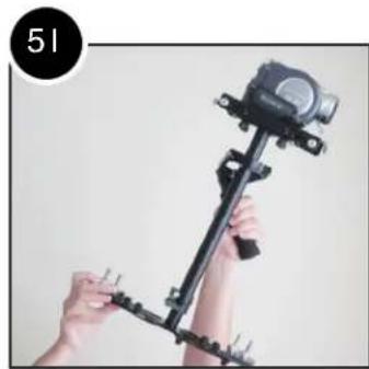 Person holding a black tripod-mounted camera rig with a mounted camera (no text or symbols visible)