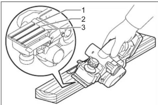 Technical diagram showing a hand operating a lathe machine with three labeled parts, including a magnified inset of the mechanical component.