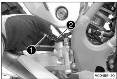 Mechanical assembly photo showing a hand adjusting components with numbered callouts and labeled section A00496-10