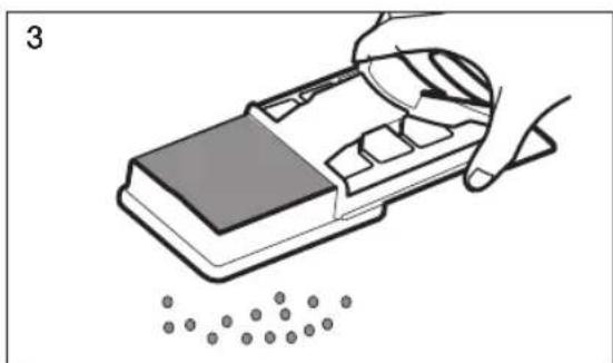 Illustration of a hand using a tool to add granular particles into a device, no text or symbols.