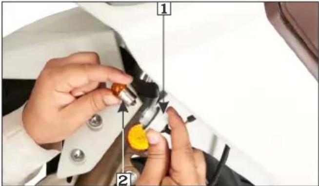 Close-up of hands installing or adjusting a component with numbered callouts and arrows indicating steps 1 and 2.