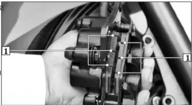 Close-up of hands assembling a mechanical component with numbered annotations pointing to parts 1 and 2.