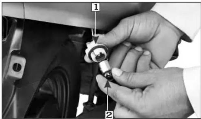 Close-up of hands installing a car component with numbered parts labeled 1 and 2