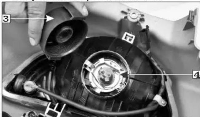 Close-up of a car engine bay with numbered parts and labeled components, showing hand operating the component.