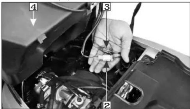 Close-up of a car engine bay with numbered parts and a hand holding a tool, likely indicating repair or maintenance.