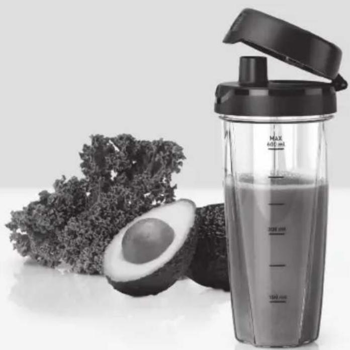 Black-and-white photo of a glass blender with a lid, whole avocado, and leafy greens in the background (no text or symbols visible)