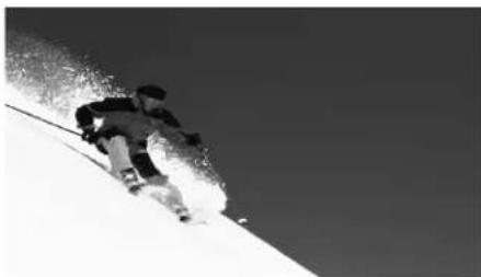 Black and white photo of a skier ascending a snowy slope under a clear sky (no text or symbols visible).