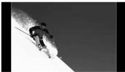 Black and white photo of a skier descending a snowy slope under clear sky (no text or symbols visible)