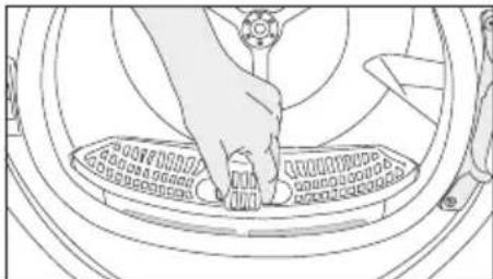 Line drawing of a hand pressing down on a circular mechanical component (no text or symbols)