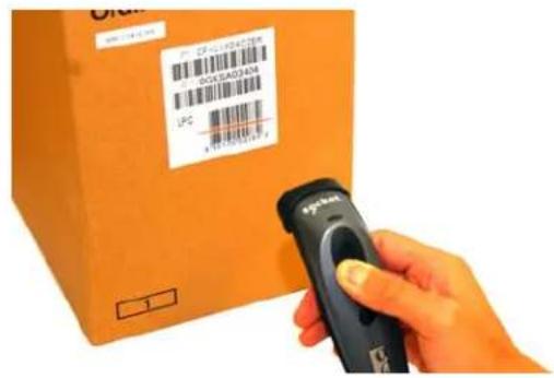 Hand holding a barcode scanner next to an orange shipping box with visible labels and barcode