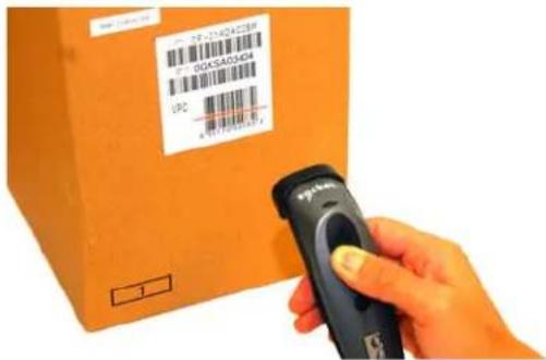 Hand holding a barcode scanner scanning an orange shipping box with visible labels and logos