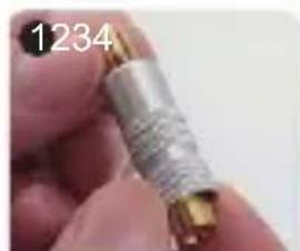Close-up of a hand holding a metallic cylindrical connector (no visible text or symbols)