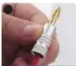 Close-up of a hand holding a metallic connector with a red handle (no visible text or symbols)