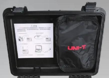 Black-and-white photo of a UNI-T device case with instructional posters and a labeled bag, showing technical diagrams and text.