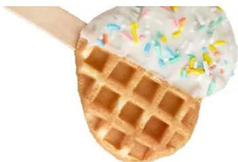 Close-up of a waffle with whipped cream and colorful toppings, being cut with a wooden stick (no text or symbols visible)