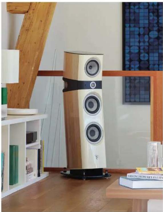 Modern multi-tiered speaker tower in a minimalist room with wooden beams and bookshelves (no visible text or symbols)