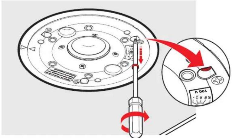 Diagram showing a screwdriver adjusting a circular mechanical component with a magnified view of the device's rotary dial.