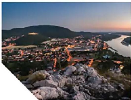 Aerial night view of a town nestled on rocky hills with a river in the background (no visible text or symbols)