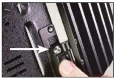 Close-up of a hand pressing a button on a black electronic device with ventilation slots (no visible text or symbols)