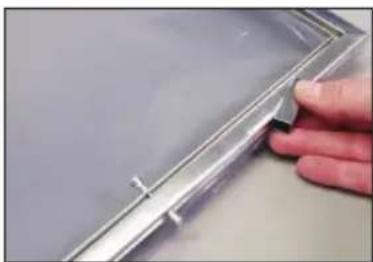 Close-up of a hand holding a transparent plastic clip against a plain background (no text or symbols visible)
