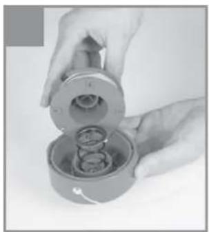 Close-up of hands holding a mechanical component with internal gears (no visible text or symbols)