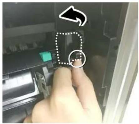 Close-up of a hand pressing a button on a device, with an arrow and dotted circle highlighting a specific area.