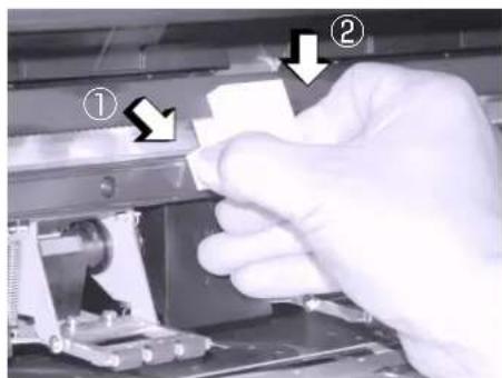 Close-up of a gloved hand pressing a component with numbered annotations (① and ②) indicating process steps.