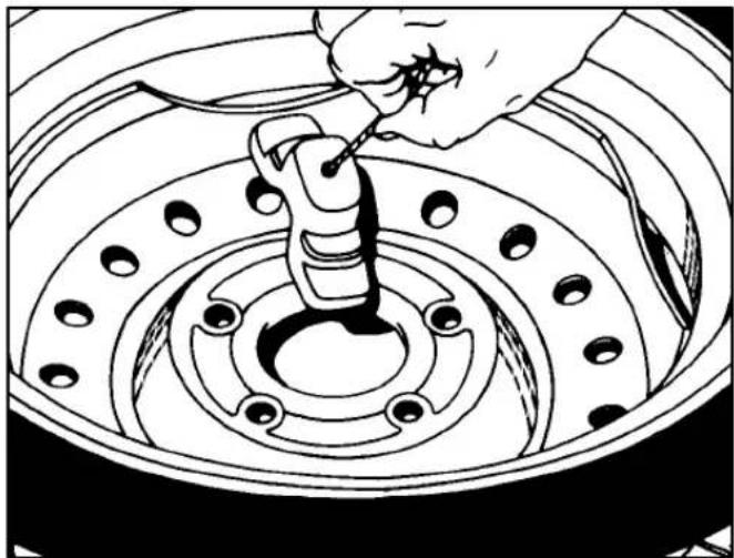 Line drawing of a hand using a tool to adjust or install a car tire component (no text or symbols present)