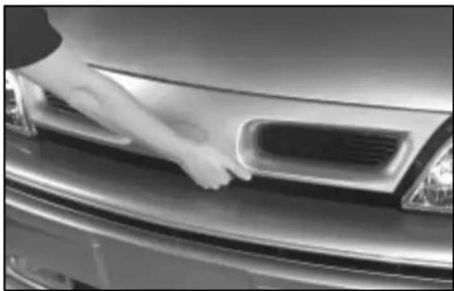 Close-up of a hand cleaning the car's front grille (no text or symbols visible)