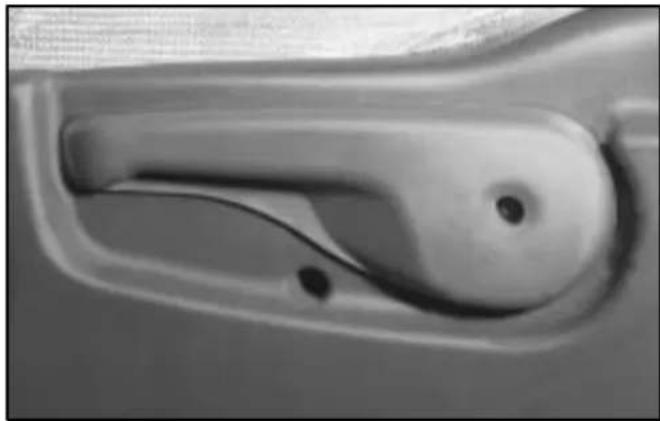 Close-up of a car handle with a black dot and curved handle (no text or symbols visible)