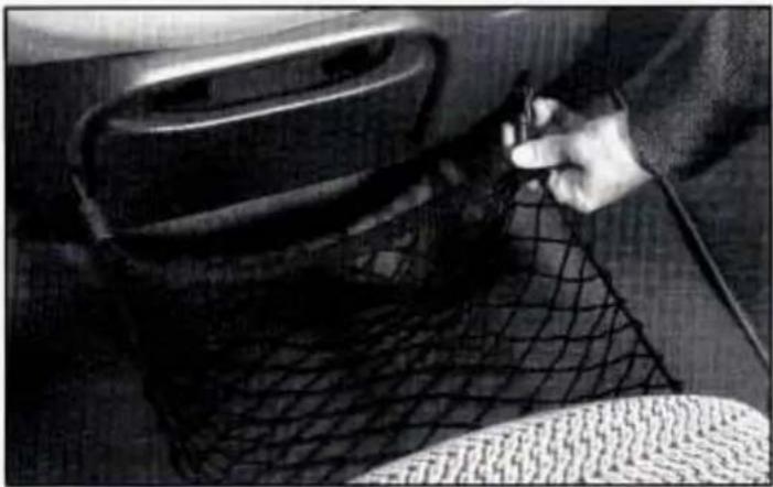 Close-up of a hand using a tool to wire meshing a car interior (no visible text or symbols)