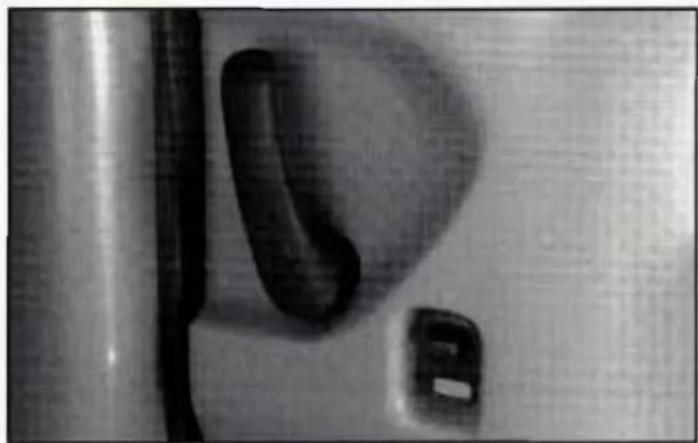 Close-up of a white mechanical component with a curved black part, possibly a valve or knob (no visible text or symbols)