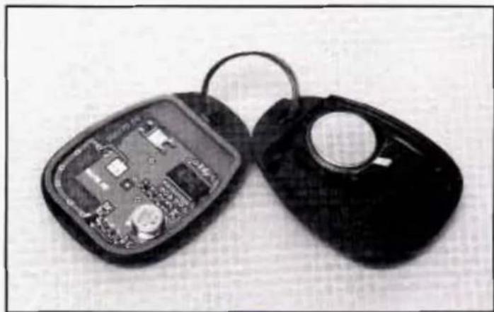 Two black electronic keys with exposed internal circuit board and circular port, placed on a plain surface (no text or symbols visible)