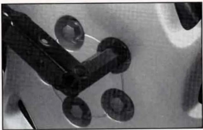 Close-up of mechanical components including a black tool and four circular components on a textured surface (no visible text or symbols)