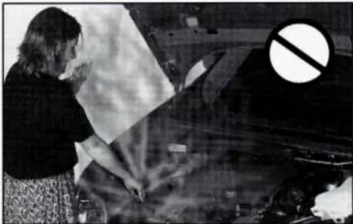 Black-and-white photo of a person cleaning a car with a large 'no' symbol overlay (no readable text or symbols)