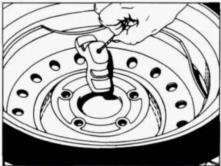 Line drawing of a hand using a tool to adjust or install a car tire component (no text or symbols present)