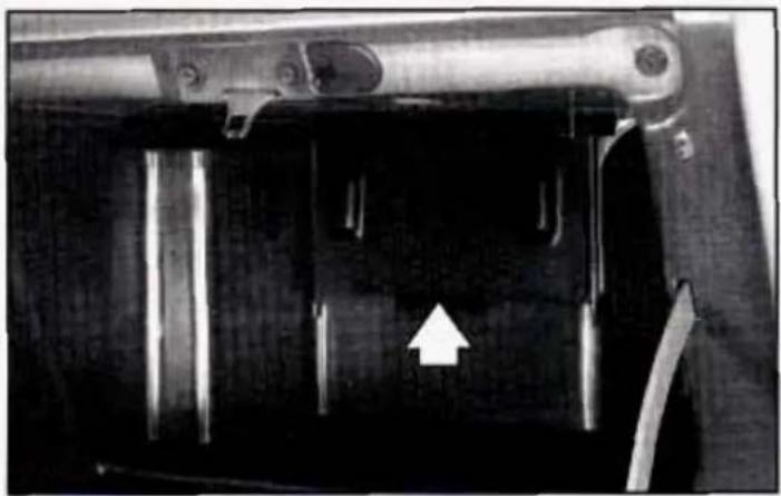 Close-up of a mechanical component with a white arrow pointing to a specific part (no visible text or symbols)