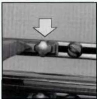 Close-up of a mechanical component with a downward arrow indicating compression or disassembly (no text or symbols visible)