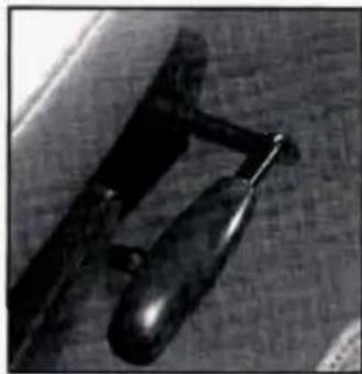Close-up of a dark, textured object with a curved handle and pointed tip, resting on a textured surface (no visible text or symbols)